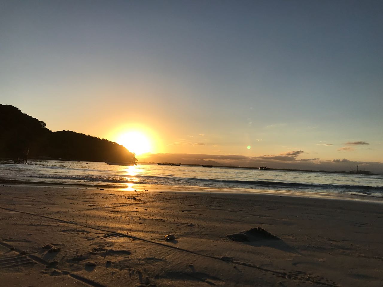 Pôr do sol na praia de Encantadas, com barcos ao fundo